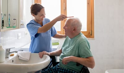 Caregiver assisting a senior man in a bathroom