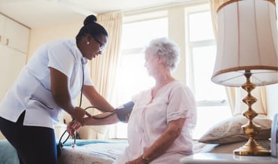 Nurse taking blood pressure of a resident in a room