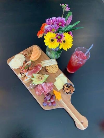 Charcuterie board with flowers and a beverage