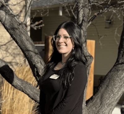 Staff member smiling outdoors near a tree