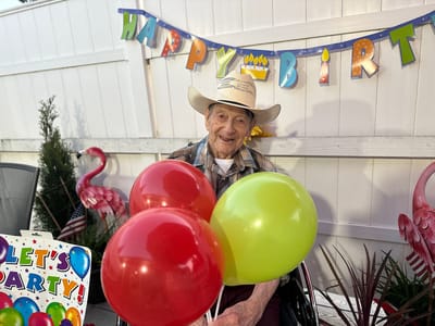 Resident celebrating with balloons at a birthday party.