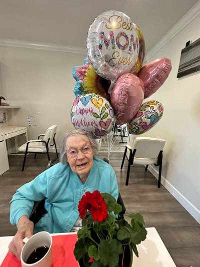 Elderly woman with balloons and a flower