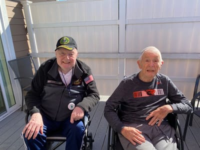 Two elderly men sitting outside in wheelchairs.