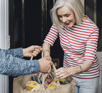 Senior woman smiling while receiving a bag of goods