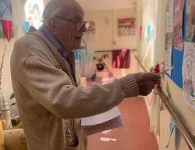 Elderly man engaging with bulletin board activities.