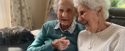 Two elderly women smiling and chatting together