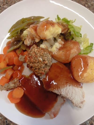 A plated meal with turkey, vegetables, and cornbread