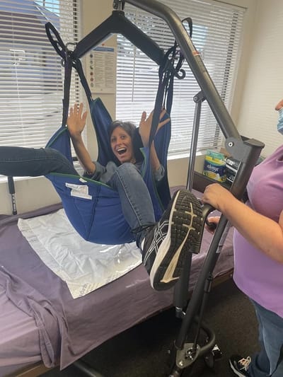 Staff assisting resident with a lift in a room