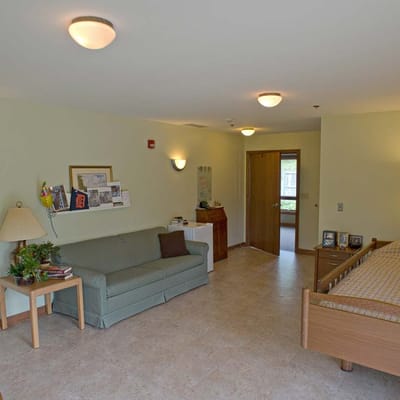 Cozy interior of a resident room with a bed and seating area.