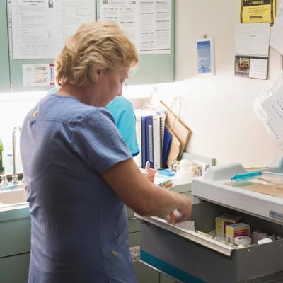 Staff member organizing medication in a facility.