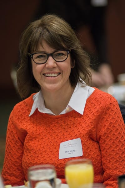 Smiling woman wearing an orange sweater at a gathering.