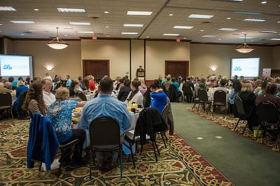 Large gathering of people at tables in a hall