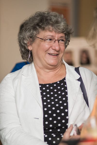 Smiling woman with curly hair in a social setting.
