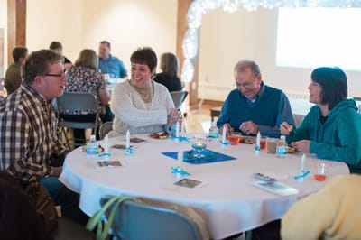 Residents and staff engaged in conversation at a table.