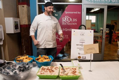 Chef presenting food at a community event.