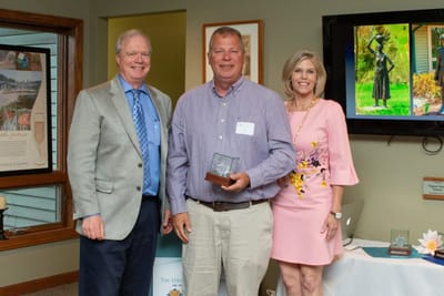 Three people at an award ceremony indoors.