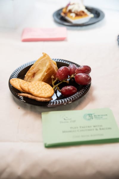 A plate of grapes, cookies, and pastry on display.
