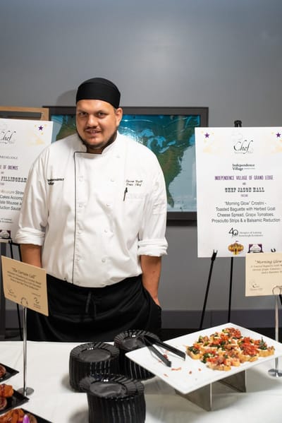 Chef presenting a gourmet dish at a dining event.