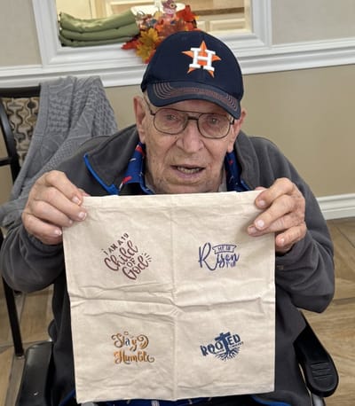 Resident holding a decorated cloth with inspirational quotes.