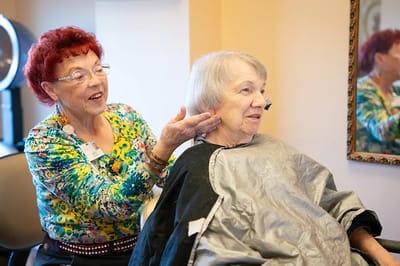 Resident getting a haircut with assistance in the salon