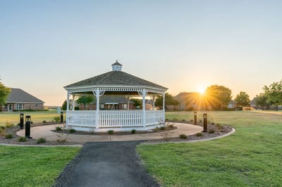 A gazebo in a landscaped outdoor area at sunset