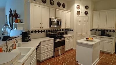 Bright kitchen area with white cabinets and stainless appliances