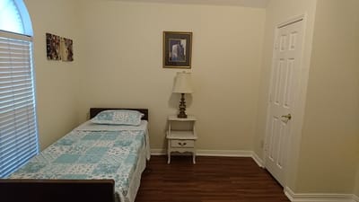 A simple private resident room with a bed and lamp
