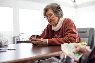 An elderly woman playing cards at a table