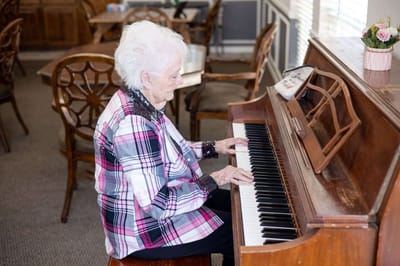 Resident playing piano in a cozy common area