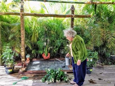 A resident watering plants in a garden area
