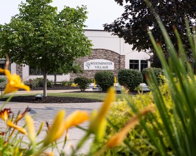 Exterior view of Westminster Village with flowers in the foreground
