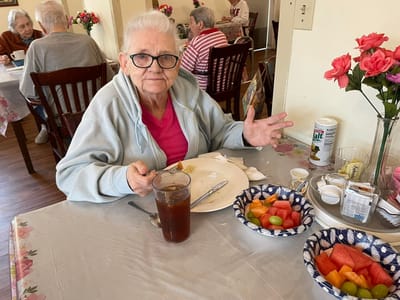 Resident enjoying a meal with fresh fruit at a dining table