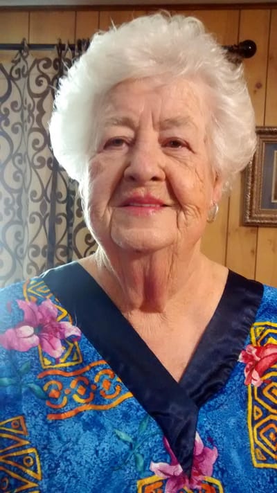 An elderly woman smiling in a colorful blouse