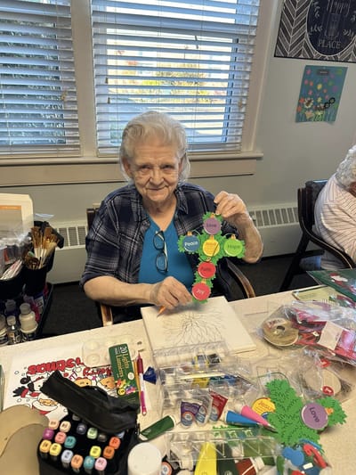 Elderly resident crafting colorful tree with positive words