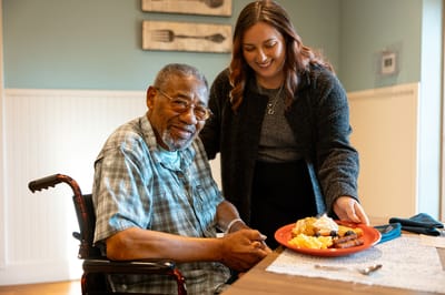 Resident with staff member enjoying a meal together