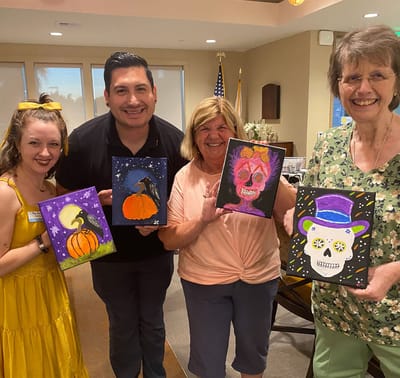Residents and staff holding up their artwork in a common area