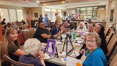 Residents and staff engaged in a painting activity in a common area