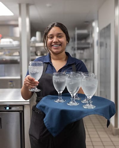 Staff member serving water in the dining area