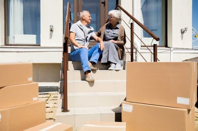 Two residents sitting on steps outside with moving boxes