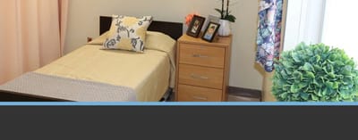 Well-furnished private resident room with a bed and dresser