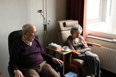 Two seniors relaxing in comfortable chairs by a window