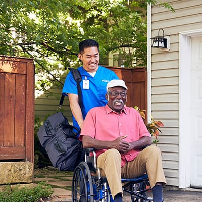 Caretaker assisting a resident in a wheelchair outdoors