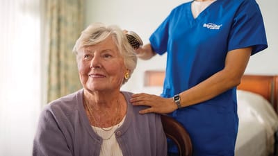 A caregiver styling a resident's hair in an interior setting