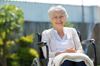 A smiling resident in a wheelchair enjoying an outdoor space