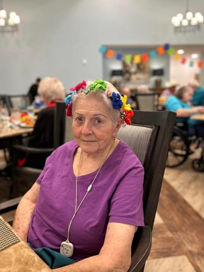 Resident with floral headband in a vibrant activity room