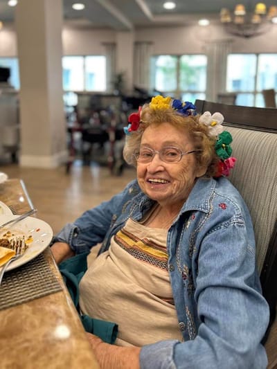 A resident smiling at the dining table with a colorful headband