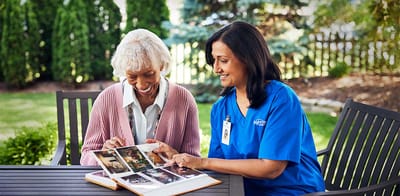 A caregiver and resident looking at a photo album outdoors