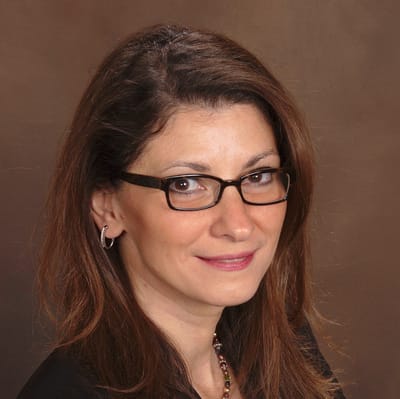 A woman with glasses smiling at the camera