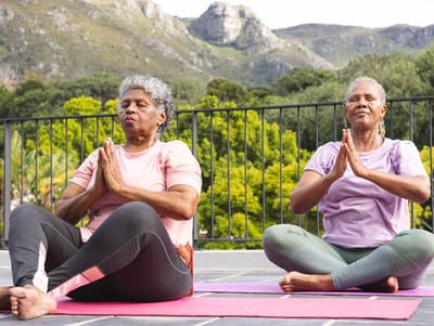 Two women practicing yoga outdoors on mats