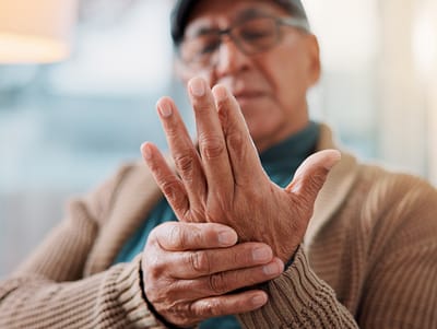 Senior man holding his wrist in a living room
